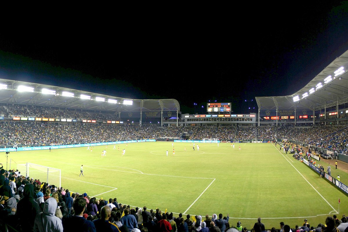 A football stadium packed with fans under floodlights at night